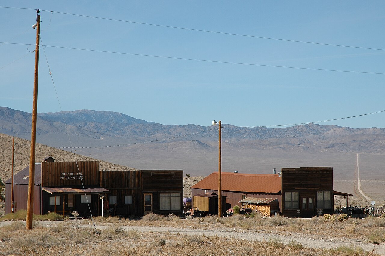 Wooden buildings at Gold Point, including a mercantile, on the open flat.
